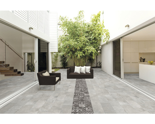 Terrasse avec carrelage de sol gris, meubles de salon de jardin et plantations