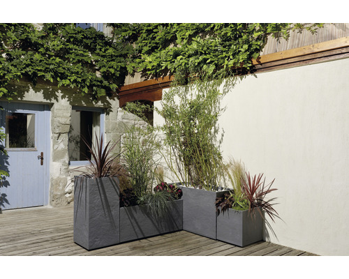 Drei groe Steengoed-Planzkëschte mat Bepflanzung am Aussenberäich.