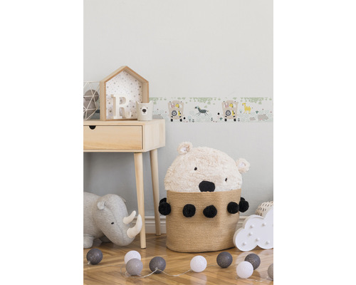 Kinderzimmer mit Holztisch, Bärenkorb, Stofftier Nashorn und Tiermotiv Bordüre