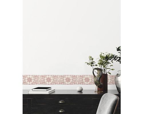 Dekorative Bordüre mit floralem Muster an einer Wand über einem schwarzen Schreibtisch