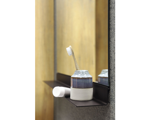 Brosse à dents dans un gobelet sur une étagère dans la salle de bain
