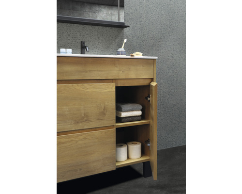 Meuble sous-lavabo avec porte ouverte, serviettes et papier toilette dans la salle de bain