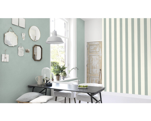 Pièce lumineuse avec table à manger, miroirs au mur et papier peint rayé