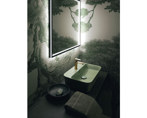 Badezimmer mit beleuchtetem Spiegel, Waschbecken, Armatur, Seifenschale und Handtuch