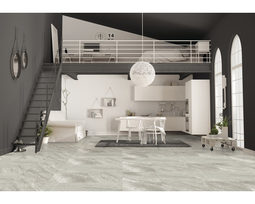 Salon lumineux avec escalier menant à un deuxième étage avec coin chambre, adjacent à une cuisine.