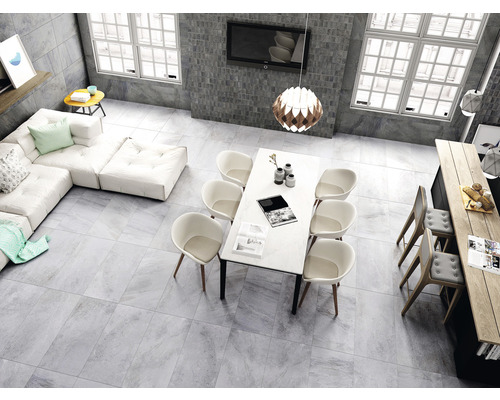 Helles Wohnzimmer mit grauen Fliesen, Ecksofa, Esstisch und Stühlen.