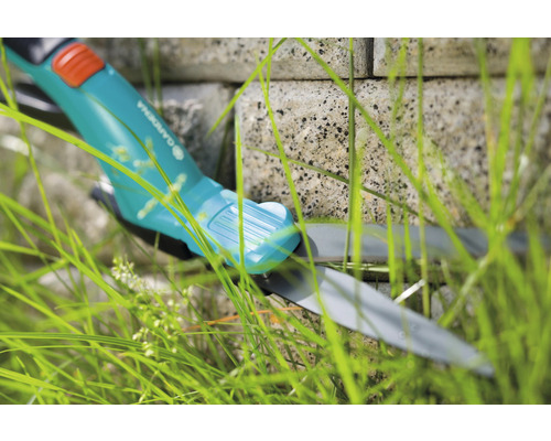 Gardena Grasschere im Gras vor einer Steinmauer