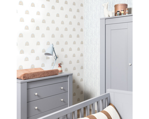 Une chambre d''enfant avec une commode à langer, une armoire et un mur avec un motif arc-en-ciel.