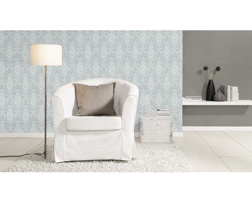 Salon avec fauteuil, lampadaire et papier peint à motifs