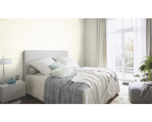 Chambre lumineuse avec lit, table de chevet et papier peint à motifs