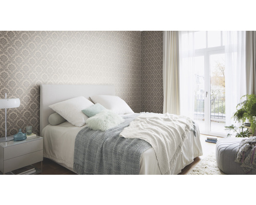 Chambre avec papier peint à motifs, lit et table de chevet
