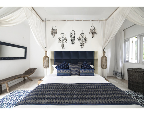 Schlafzimmer mit Doppelbett, Nachttischlampen, Traumfängern und blauen Textilien