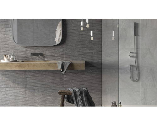 Salle de bain moderne avec carrelage mural gris, lavabo en bois et douche.