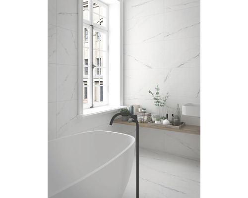 Modernes Badezimmer mit weißer Badewanne, Armatur und Wandfliesen in Marmoroptik