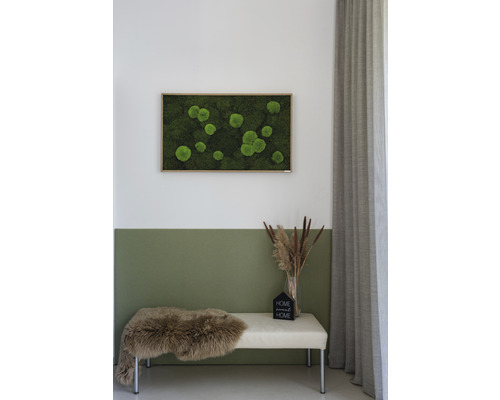 Dekoratives Moosbild mit Rahmen über einer Sitzbank mit Fell und Dekoration