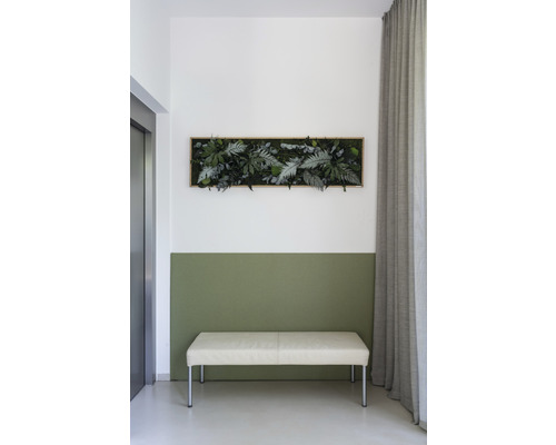 Wanddekoration mit künstlichen Pflanzen über einer Bank in einem hellen Raum