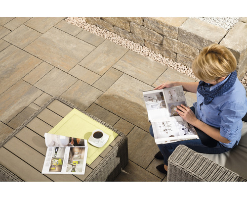 Terrasse mit Pflastersteinen, Steinen und Frau mit Zeitschrift