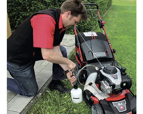 Un homme fait le plein d''huile dans une tondeuse à gazon