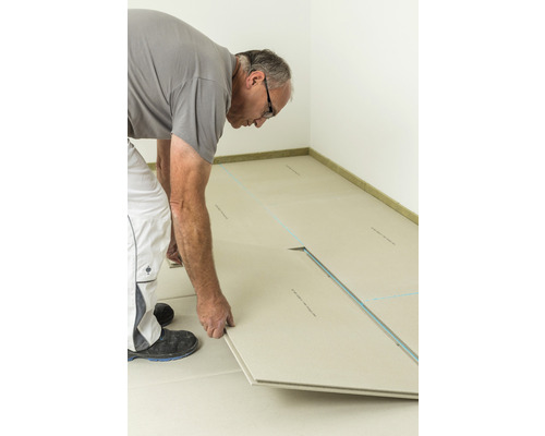 Handwerker verlegt Trockenestrich-Elemente in einem Raum