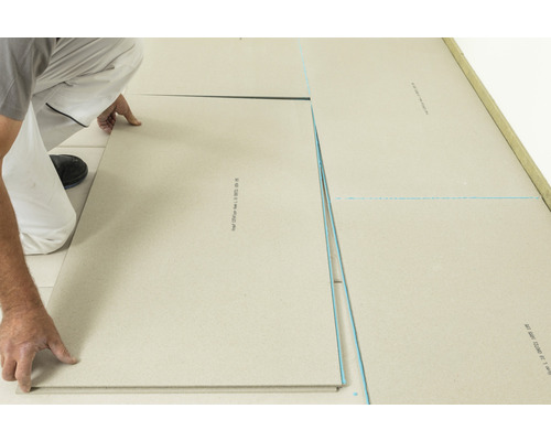 Mann verlegt Trockenestrichplatten auf einem Boden