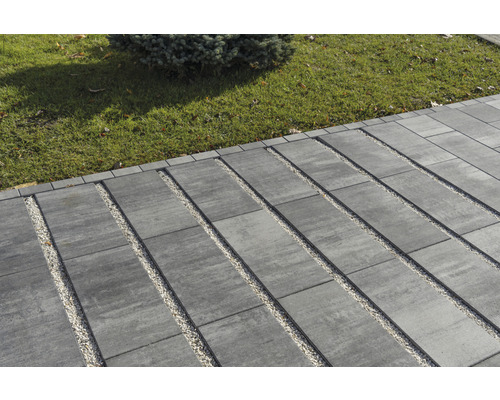 Aussenbereich mit Pflastersteinen und Kiesstreifen neben einer Rasenfläche