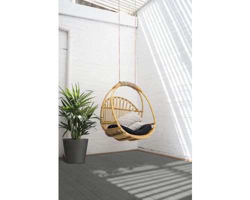 Fauteuil suspendu en rotin avec coussins et plante sur terrasse