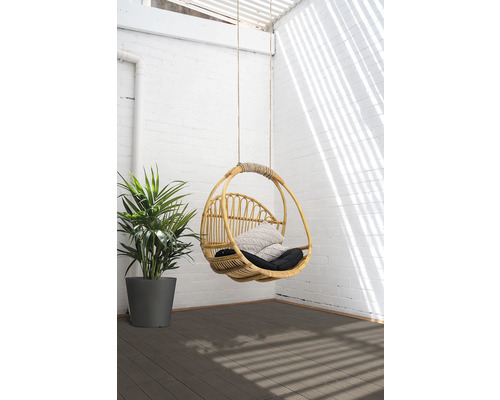 Fauteuil suspendu en rotin avec coussins et plante sur une terrasse