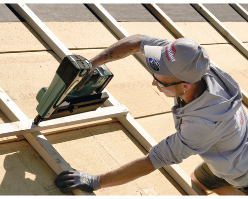 Handwerker befestigt Dachlatten mit einem Druckluftnagler auf einem Dach