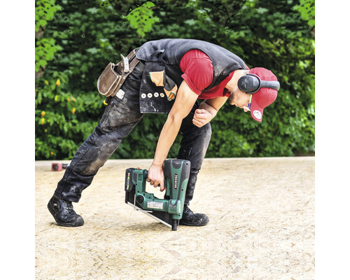 Ein Handwerker benutzt einen Akku-Nagler auf einer Holzoberfläche.