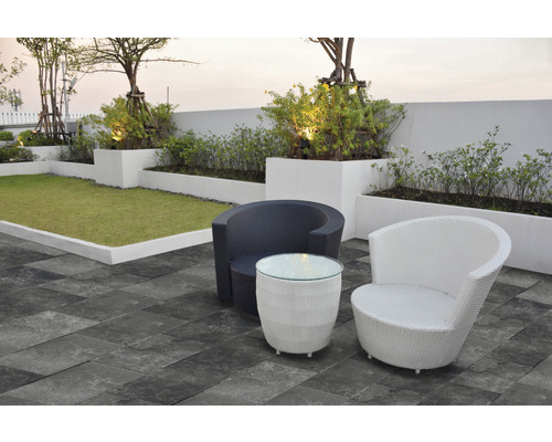 Scène avec deux fauteuils en rotin et une table sur une terrasse avec pelouse