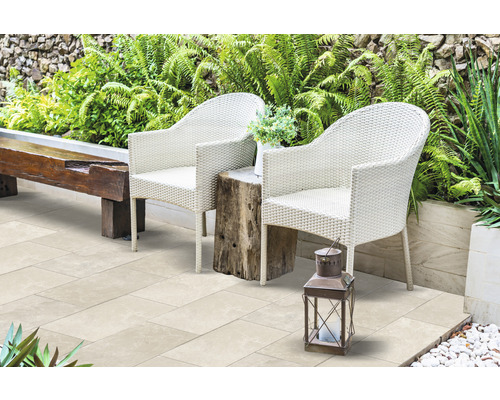 Terrasse mit zwei Rattansesseln, einem Holztisch und einer Laterne im Garten.