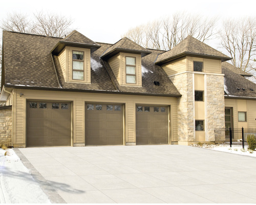 Ansicht eines Hauses mit drei Garagentoren und Steinfassade