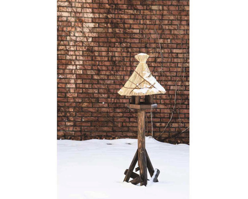 Maison pour oiseaux en bois avec toit de chaume dans un jardin enneigé