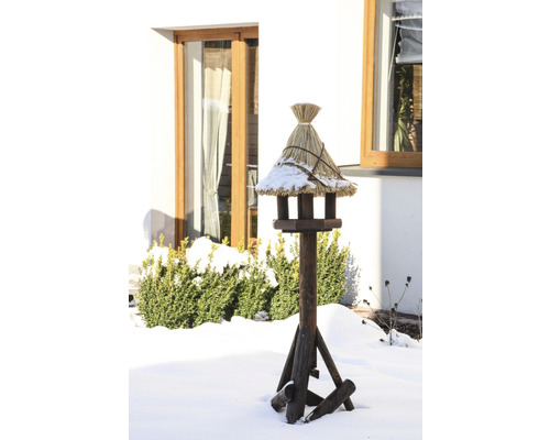 Mangeoire en bois avec toit de chaume dans un jardin d''hiver.
