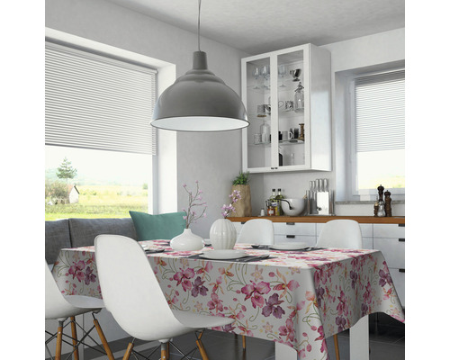 Table à manger avec une nappe fleurie dans une salle à manger lumineuse avec fenêtre et suspension