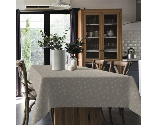 Esstisch mit gemusterter Tischdecke, Blumenvasen und Stühlen in einem hellen Raum.