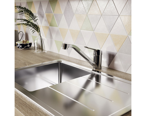 Edelstahlspüle mit Abtropffläche und Armatur vor dreieckigen Wandfliesen