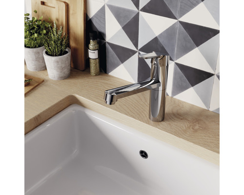 Küchenarmatur aus Metall auf einer Spüle mit gemusterten Fliesen im Hintergrund