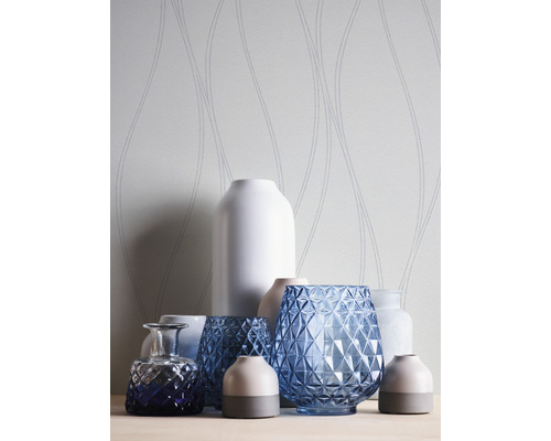 Dekorative Vasen aus Glas und Keramik vor einer gemusterten Tapete