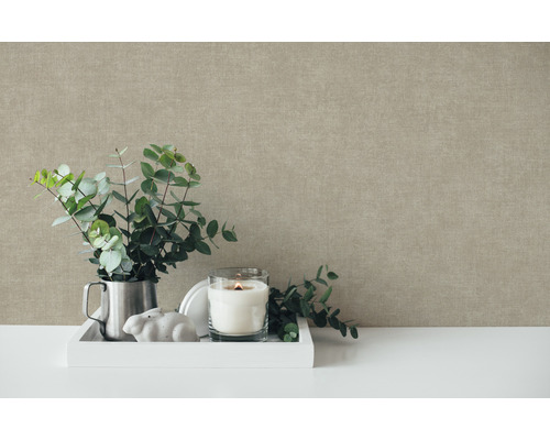 Scène de nature morte décorative avec des branches d''eucalyptus, une bougie et des éléments décoratifs devant un mur texturé
