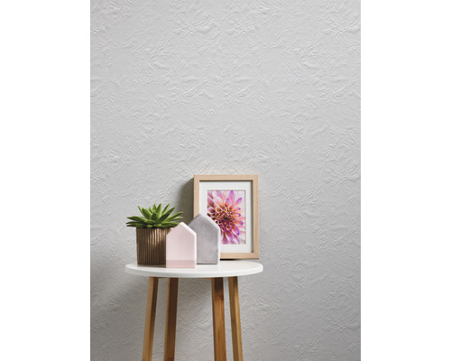 Mur clair avec papier peint texturé, table avec décoration et cadre photo