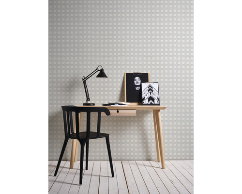 Arbeitszimmer mit Schreibtisch, Stuhl, Lampe, zwei Bilderrahmen und Tapete mit Karomuster