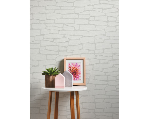 Scène avec papier peint en pierre, table, plante, cadre photo et décoration