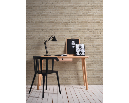 Bureau avec chaise, lampe et décoration devant un mur en briques