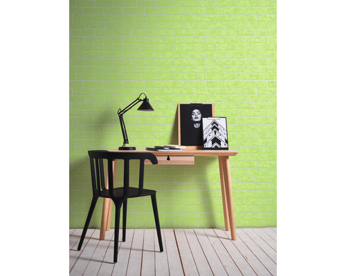 Un bureau avec un bureau, une chaise et une lampe devant un mur avec un motif de briques