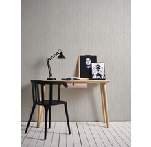 Szene mit Schreibtisch, Stuhl, Lampe und Bildern vor einer gemusterten Tapete