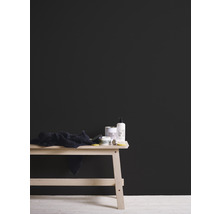 Schwarze Wandfarbe hinter einem Holztisch mit Badartikeln und Handtuch.