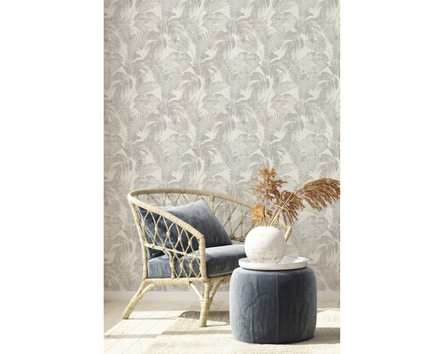 Dekoratives Zimmer mit gemusterter Tapete, Rattansessel und Hocker.