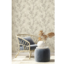 Scène avec fauteuil en rotin, tabouret et papier peint à motif végétal pour un intérieur élégant