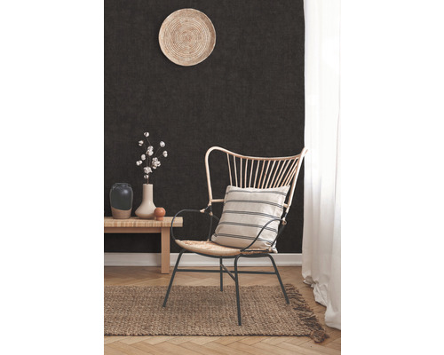 Einrichtungsszene mit einem Sessel, einem kleinen Tisch, einer Vase und einem Dekoteller an einer dunklen Wand.